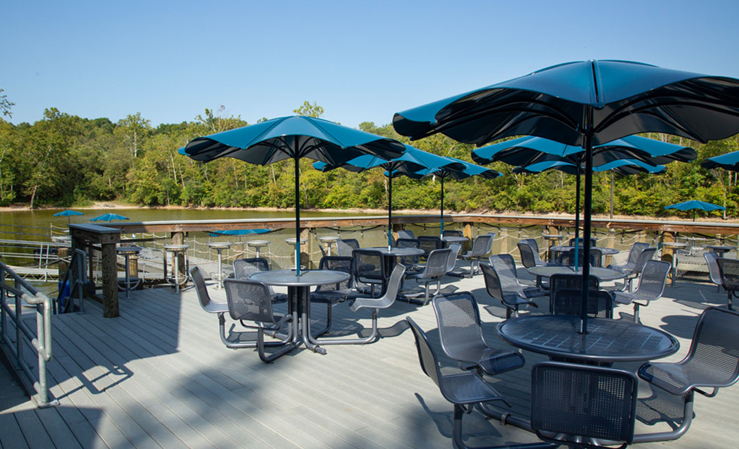 a group of tables and chairs on a deck with umbrellas