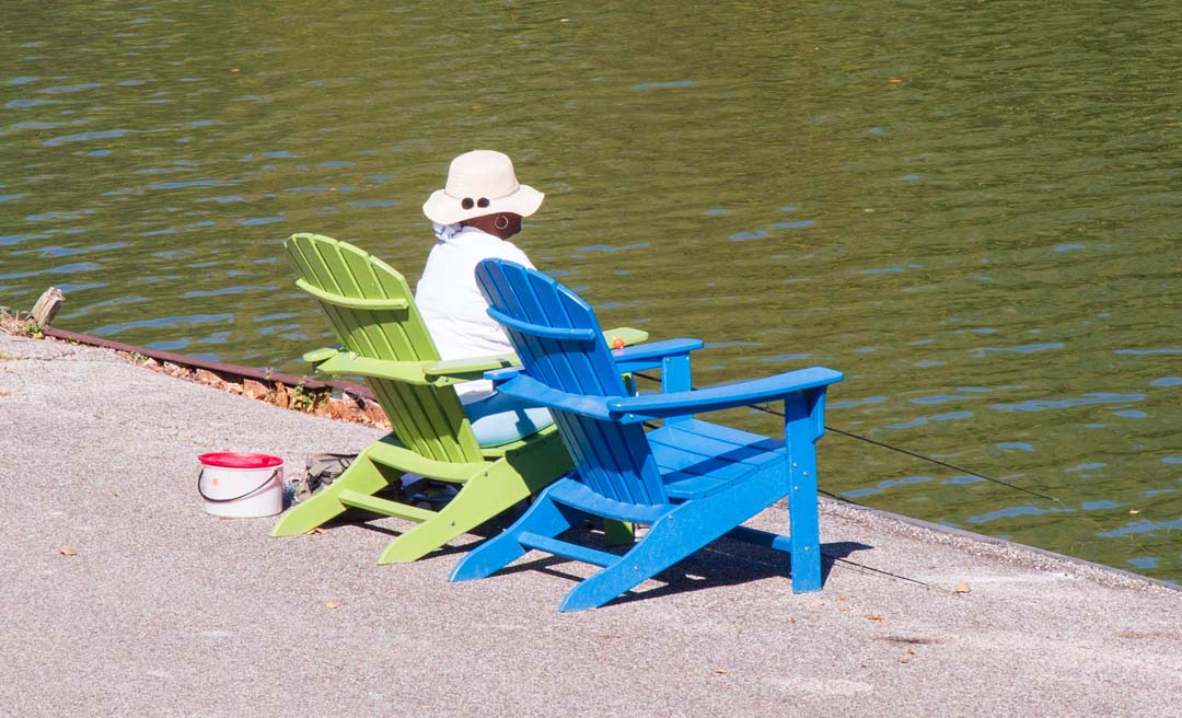 a person sitting in a chair next to a body of water