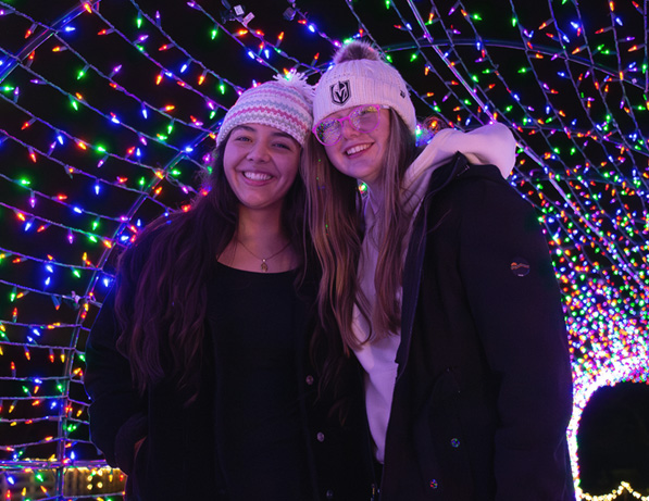 two women standing in front of a string of lights