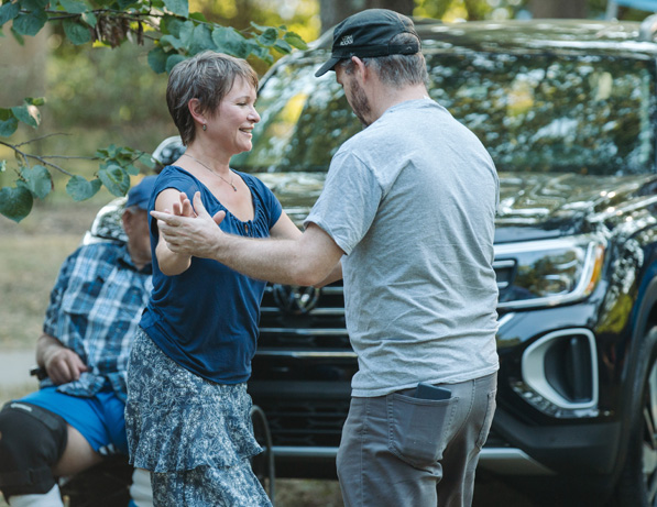 a man and woman dancing in front of a car