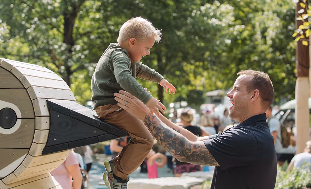 a man holding a child up to his hand