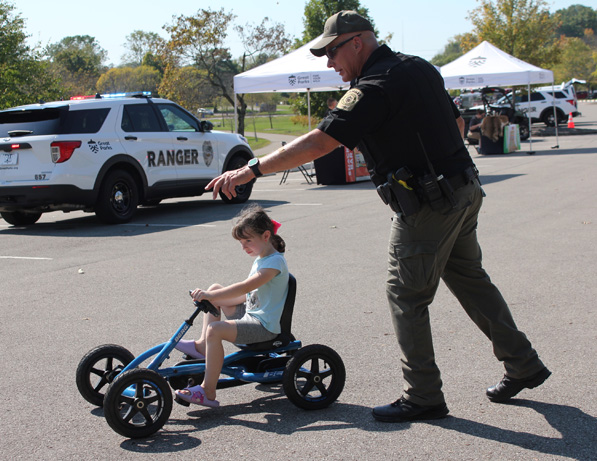 a man pushing a child on a tricycle